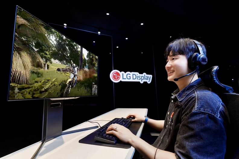 LG디스플레이 모델이 4세대 기술이 적용된 27인치 OLED 모니터 패널로 게임을 즐기고 있다. / LG디스플레이