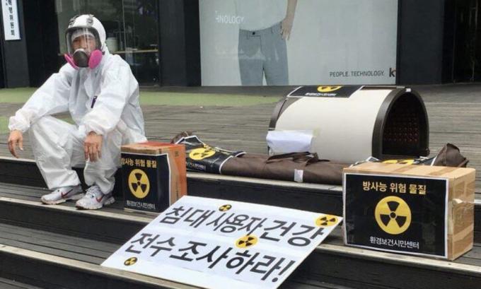 환경보건시민센터 관계자가 방독면과 방진복을 쓴 채 2018년 6월 광화문 원자력안전위원회 앞에서 라돈침대 등 생활용품의 안전문제에 대한 정부조사를 촉구하고 있다. / 환경보건시민센터